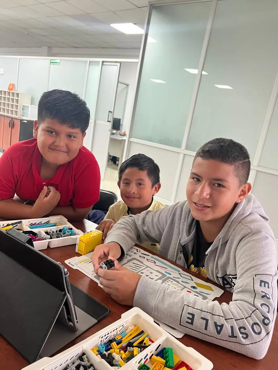 Tres niños de 10 a 12 años frente al computador en clase de programación